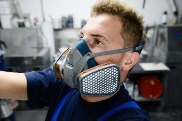 Auf dem Bild ist ein Arbeiter zu sehen, der eine Atemschutzhalbmaske mit zwei Filtern rechts und links trägt.