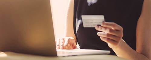 eine Frau sitzt mit einer Geldkarte vor ihrem Laptop