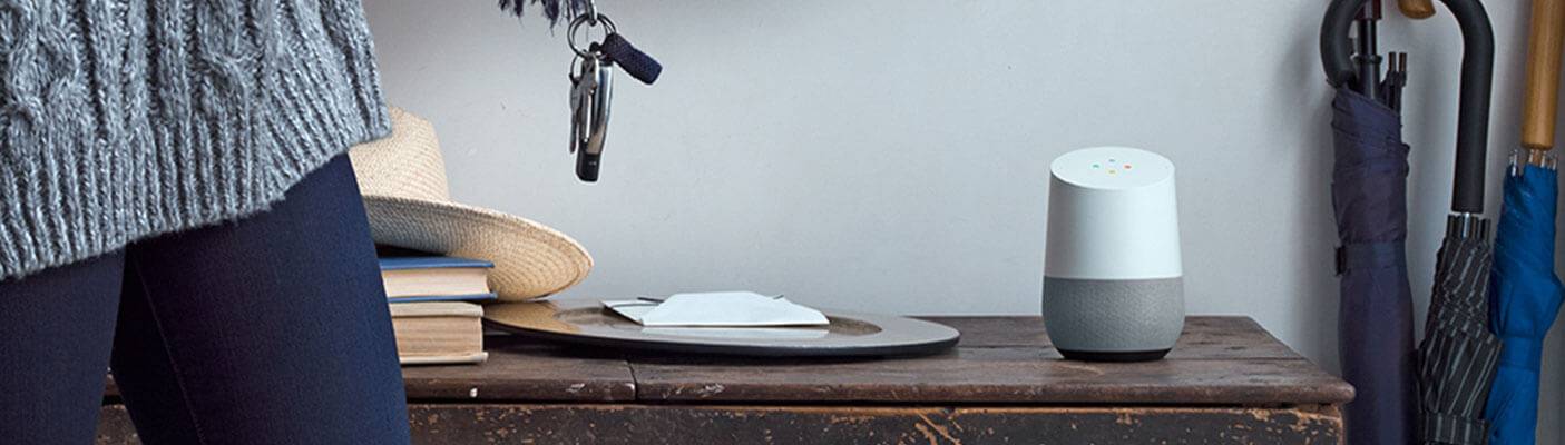 Ein smarter Lautsprecher steht auf einem Holztisch neben Briefen und Schlüsseln.