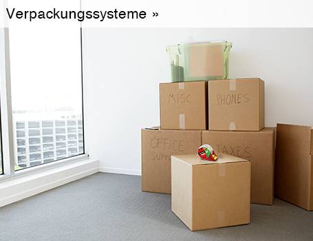  In der Ecke eines hellen Raumes mit einem großen Fenster stehen mehrere braune Umzugskartons, auf denen teilweise "MISC", "PHONES", "OFFICE SUPPLY" und "TAXES" handschriftlich vermerkt ist, und auf dem vordersten Karton liegt ein Abroller für Klebeband; der Text "Verpackungssysteme »" im oberen linken Bereich des Bildes weist auf eine Weiterleitung hin.