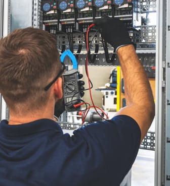 Ein Elektriker misst mit einem Multimeter in einem Schaltschrank elektrische Werte.