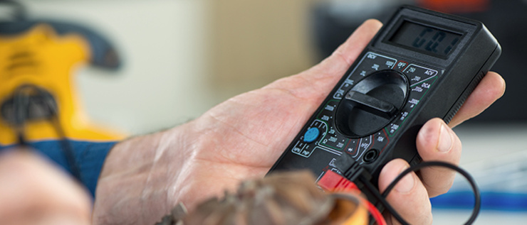 Nahaufnahme einer Hand, die ein digitales Multimeter hält und die Anzeige zeigt 52.
