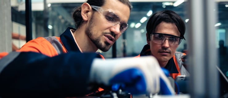 Zwei Fachkräfte in Schutzkleidung arbeiten gemeinsam an einer technischen Anlage