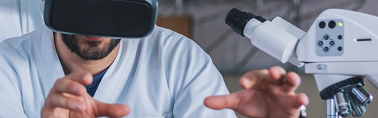 Abb. Gruppe von Ärzten, die medizinische Daten auf Tablets im Labor analysieren, im Fokus eine Person mit VR-Brille