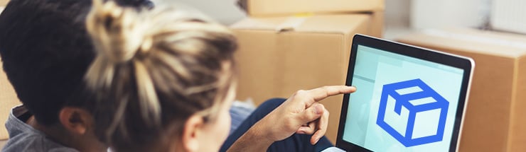 Zwei Personen schauen auf einen Laptop mit Paket-Symbol, im Hintergrund stehen Umzugskartons.