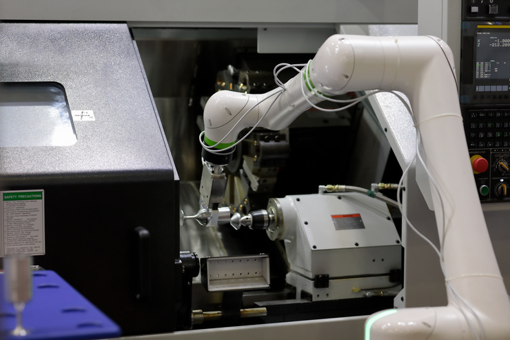 Ein Roboterarm arbeitet in einer technischen Maschine in einem Labor oder Fertigungsraum.