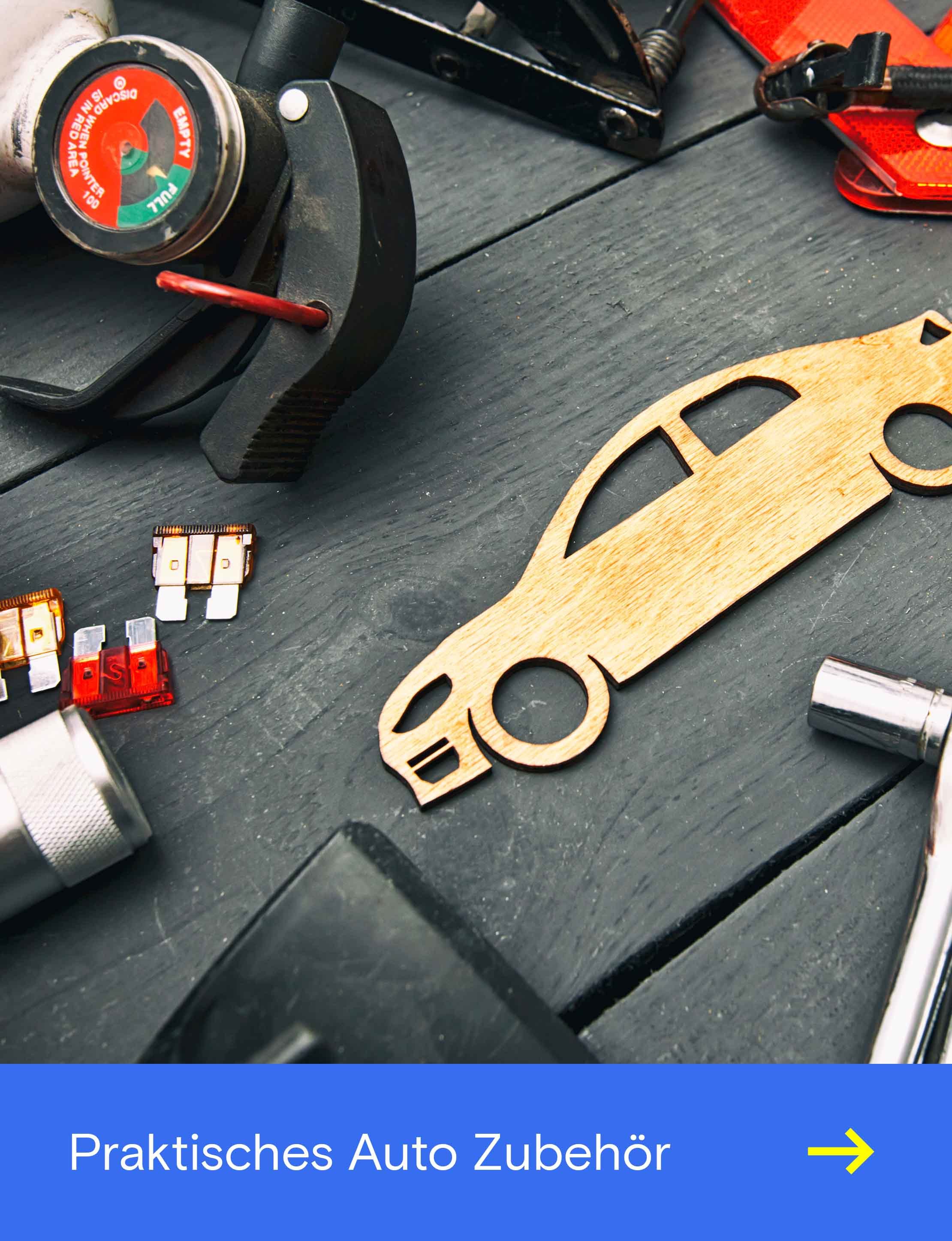 Verschiedene Werkzeuge und Autozubehörteile liegen auf einer Werkbank neben einer hölzernen Autoform.