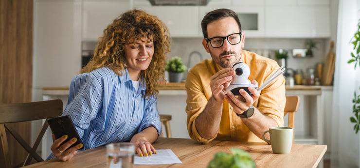 Paar richtet gemeinsam eine smarte Überwachungskamera ein und nutzt dafür ein Smartphone.