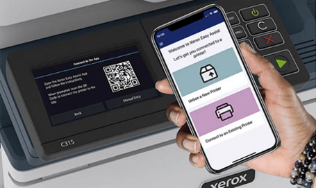 Eine Hand hält ein Smartphone mit der Willkommensseite der Xerox Easy Assist App vor einen Xerox C315 Drucker, dessen Display einen QR-Code zum Verbinden mit der App anzeigt.