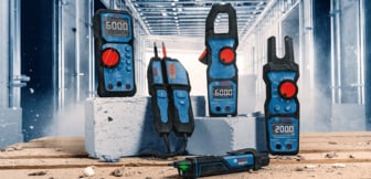  Vier Bosch Professional Messgeräte stehen auf Ziegelsteinen und einem Holzboden in einer Baustellenumgebung.