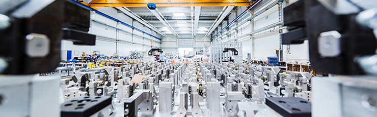 Innenansicht einer modernen Fertigungshalle mit zahlreichen Maschinen und Arbeitsstationen.