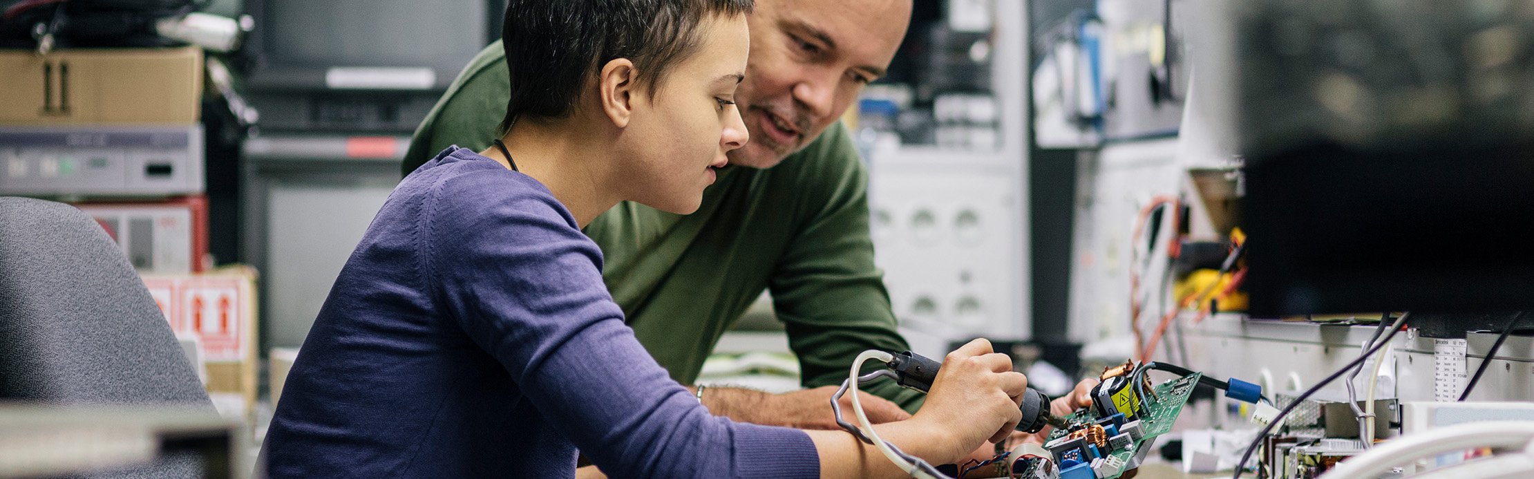 Ein älterer Mann erklärt einer jungen Person einfach eine Löttechnik.