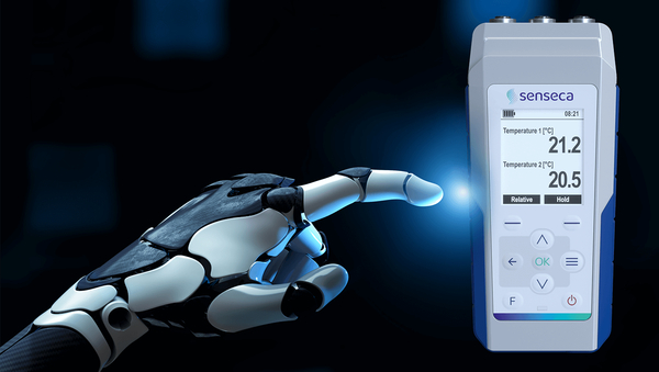 Roboterarm zeigt auf digitales Senseca Messgerät, das zwei Temperaturwerte anzeigt.