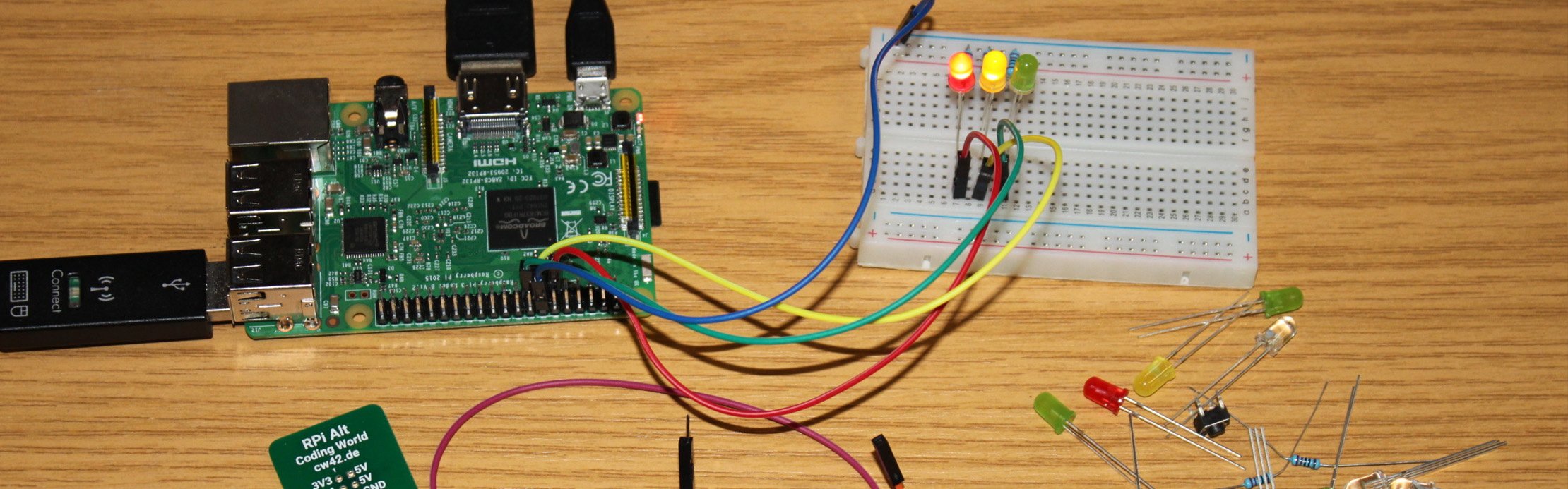 Raspberry-Pi-Platine ist über Kabel mit einem Breadboard verbunden, auf dem mehrere LEDs leuchten und elektronische Bauteile daneben liegen.