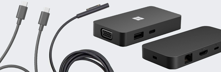 Zwei schwarze Microsoft-Dockingstationen mit verschiedenen Anschlüssen sowie mehreren Verbindungskabeln.
