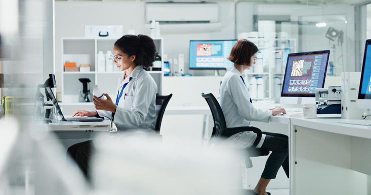 Wissenschaftlerinnen arbeiten in einem modernen Labor an ihren Computern