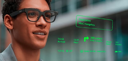 Ein junger Mann trägt eine schwarze Rokid Datenbrille, während in seinem Sichtfeld grüne Augmented-Reality-Einblendungen mit Navigationsdaten und einer Ankunftszeit zu sehen sind.