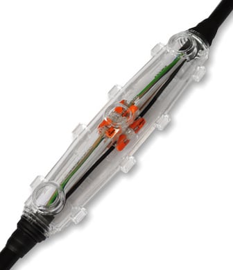 Eine transparente Verbindungsmuffe aus Kunststoff umschließt eine elektrische Kabelverbindung mit orangefarbenen Klemmen und ist vor einem weißen Hintergrund freigestellt.