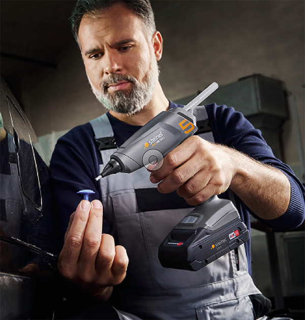 Ein Mann verwendet eine akkubetriebene Steinel Heißklebepistole, um ein kleines Teil zu kleben.