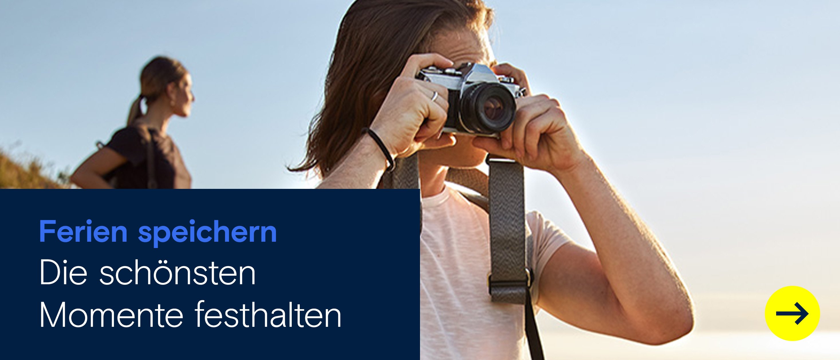 Junger Mann fotografiert mit Kamera in der Natur beim Wandern, Frau im Hintergrund mit Rucksack – Outdoor-Abenteuer und Naturerlebnis bei Sonnenuntergang