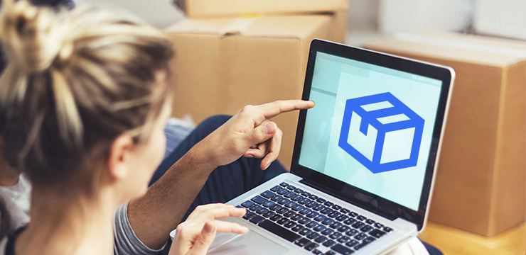 Zwei Personen schauen auf einen Laptop mit Paket-Symbol, im Hintergrund stehen Umzugskartons.