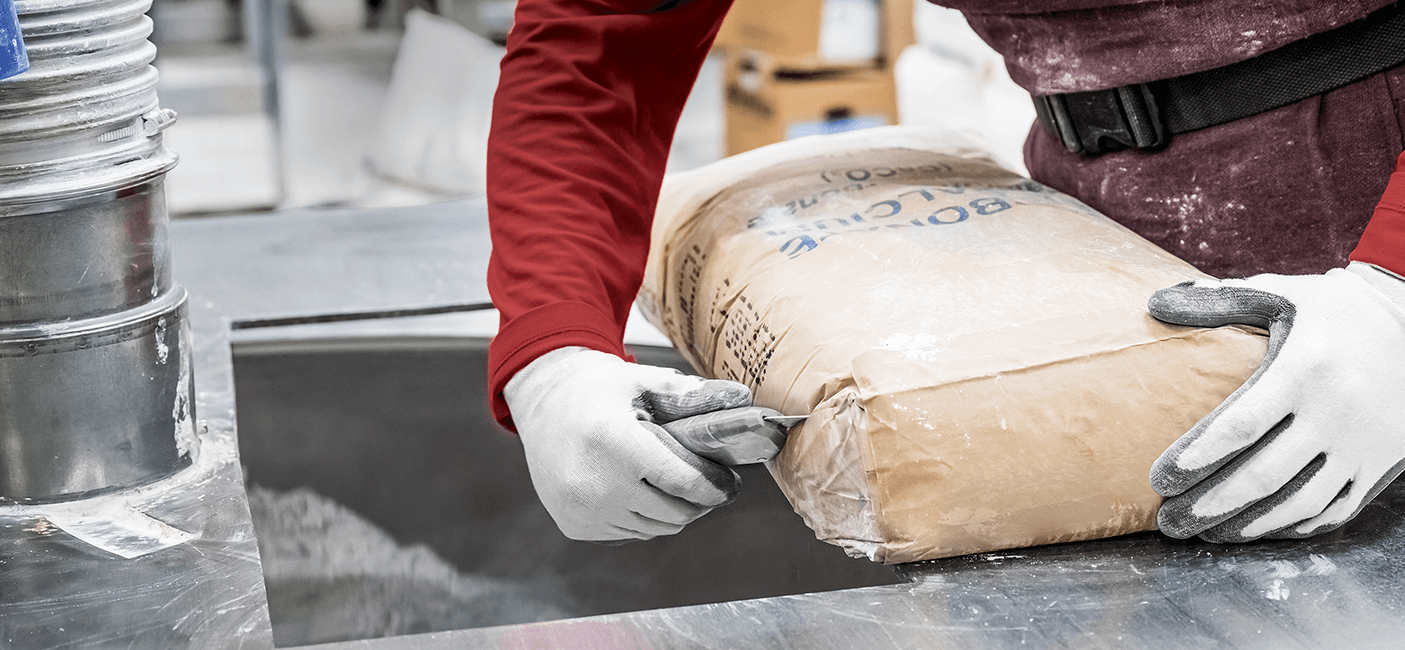 Arbeiter öffnet Sackware mit Martor Sicherheitsmesser in industrieller Umgebung.