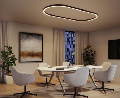 Anwendungsbeispiel 4: Dieses Bild zeigt ein modernes Esszimmer über dessen Tisch das Schienensystem in Form des Tisches als Oval an der Decke montiert ist. Die moderne, ovale Deckenleuchte verleiht dem Raum ein stilvolles Ambiente. An den Wänden hängen abstrakte Kunstwerke, die zur eleganten Atmosphäre beitragen.