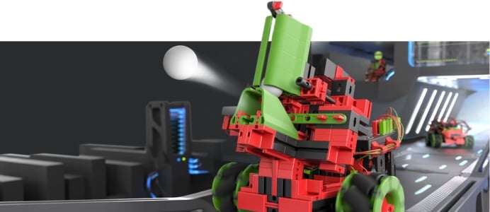 Ein roter fischertechnik Roboter, der einen weißen Ball in einer futuristischen Roboter-Arena wegschießt.