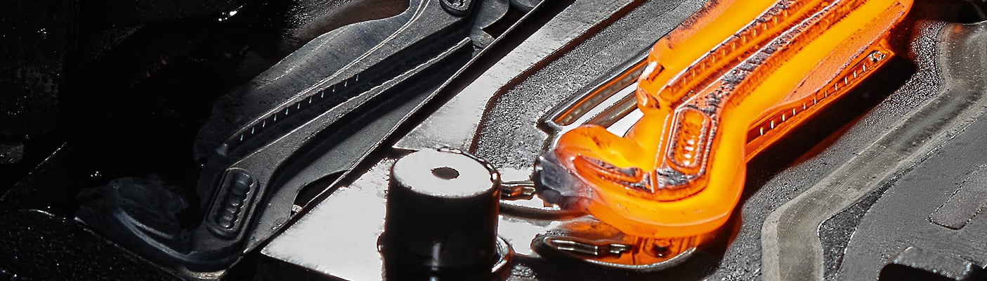 Eine Nahaufnahme eines orange glühenden Metalls, das zu einer Knipex-Zange geschmiedet wird, neben einem fertigen schwarzen Stück.