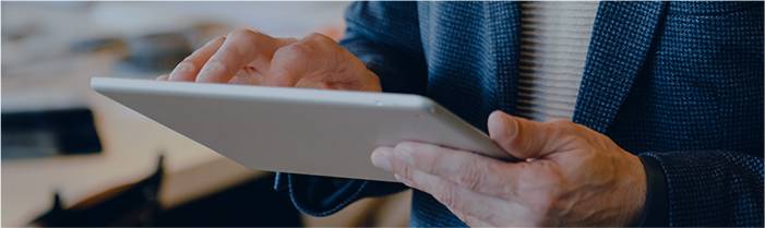 Hände, die ein Tablet in einem blauen Anzug halten. Zum E-Procurement Wiki.