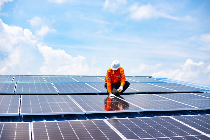 Un technicien installe des panneaux solaires sur un toit dans le cadre des technologies durables de bâtiment.