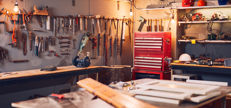 Atelier bien équipé, comprenant de nombreux outils manuels et électriques, des établis et une armoire à outils rouge.