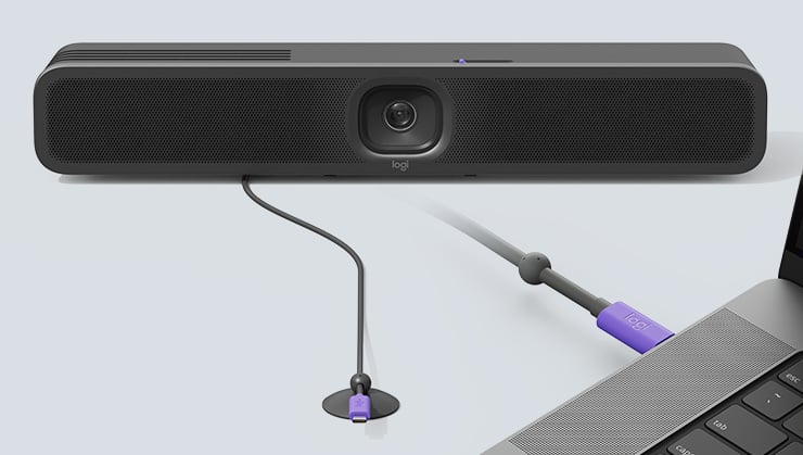 Caméra de conférence Logitech connectée à un ordinateur portable via un câble USB sur un fond clair.