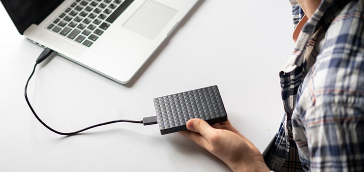 Un homme est assis dans un bureau devant un ordinateur portable et se tient la tête d'un air inquiet, apparemment à cause d'un problème informatique ou lié aux données.