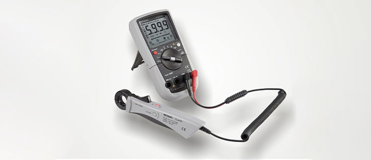 Un multimètre numérique avec des sondes, posé sur une surface blanche.