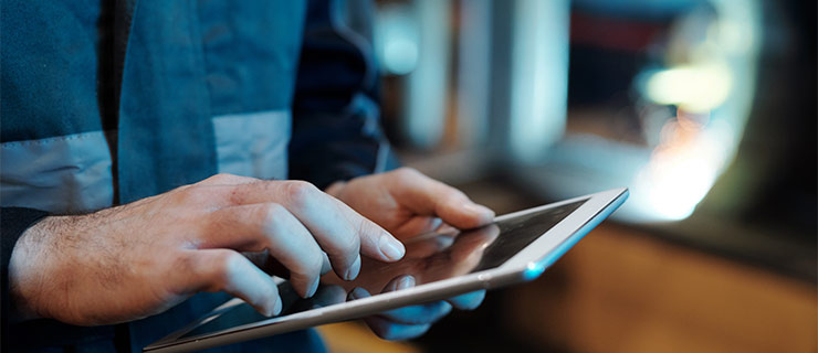 Gardien d’immeuble en tenue de travail utilise une tablette pour la planification digitale de la maintenance