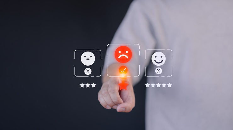 Une personne sélectionne une évaluation négative en appuyant sur un visage triste sur un écran.