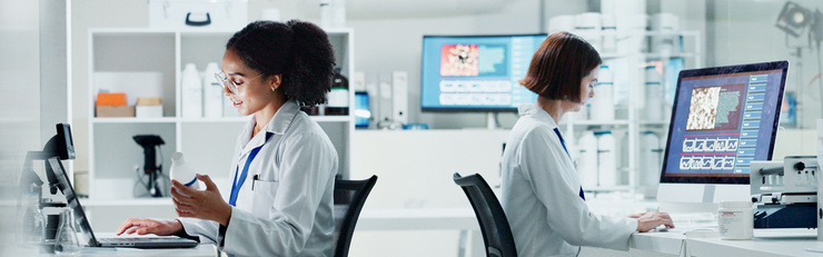 Deux scientifiques en blouses blanches travaillent sur des ordinateurs dans un laboratoire moderne.