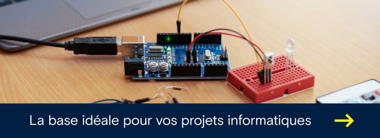 Carte de développement Arduino posée sur un bureau, connectée par USB et reliée par des câbles à une plaque d’essai rouge avec une LED.