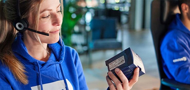 Employée de Conrad tenant un appareil électrique au sein d'un centre d'appel