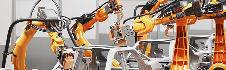 Plusieurs robots industriels orange assemblent des carrosseries de véhicules sur une ligne de production automatisée.