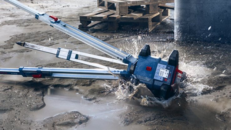 Un trépied de chantier tombe dans une flaque et éclabousse de l’eau sur un chantier.