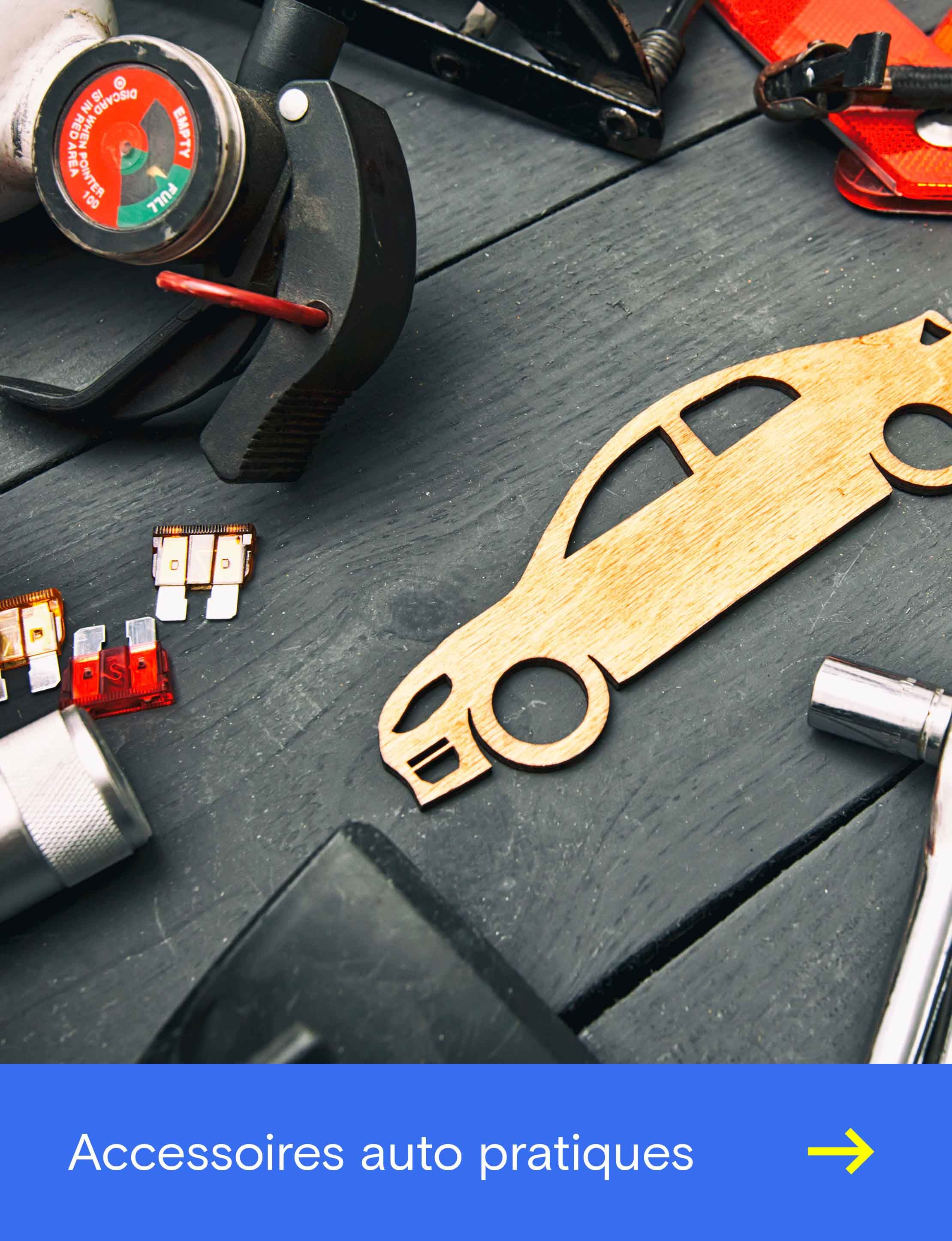 Divers outils et accessoires automobiles sont posés sur un établi à côté d’une forme de voiture en bois.