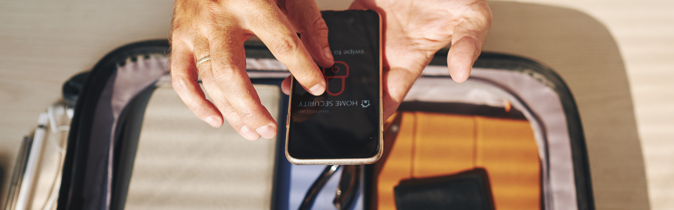 La personne active une application de sécurité sur son smartphone, tandis que ses objets de valeur sont rangés en toute sécurité dans un sac.