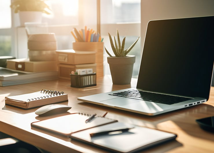 Gros plan sur une table bien rangée avec des cahiers, des plantes et un ordinateur portable