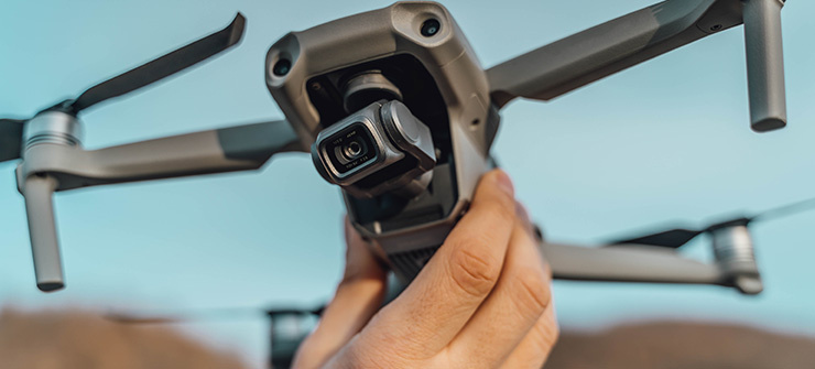 Une personne tient un drone équipé d’une caméra, prêt à décoller.