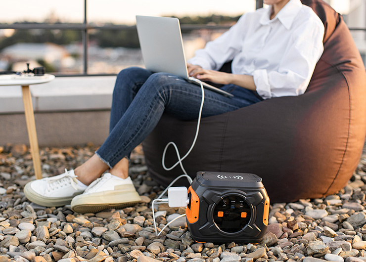 Une personne travaille à l'extérieur sur son ordinateur portable et le recharge à l'aide d'une station d'alimentation portable.