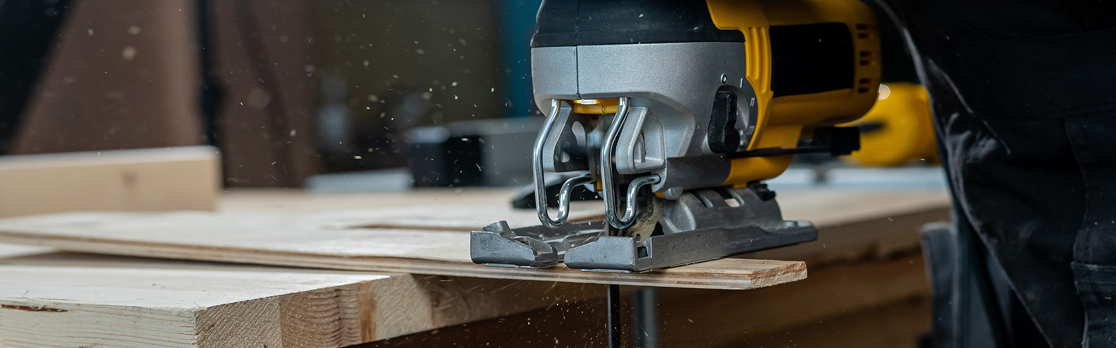 Gros plan sur une scie sauteuse effectuant une découpe précise d'un panneau de bois dans un atelier.