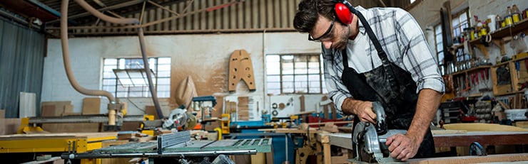 Un menuisier dans son atelier, en train d'utiliser une machine.