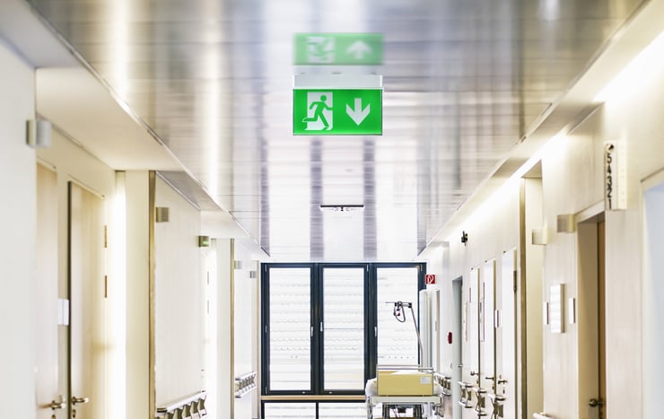Panneau vert de sortie de secours dans un couloir d’hôpital